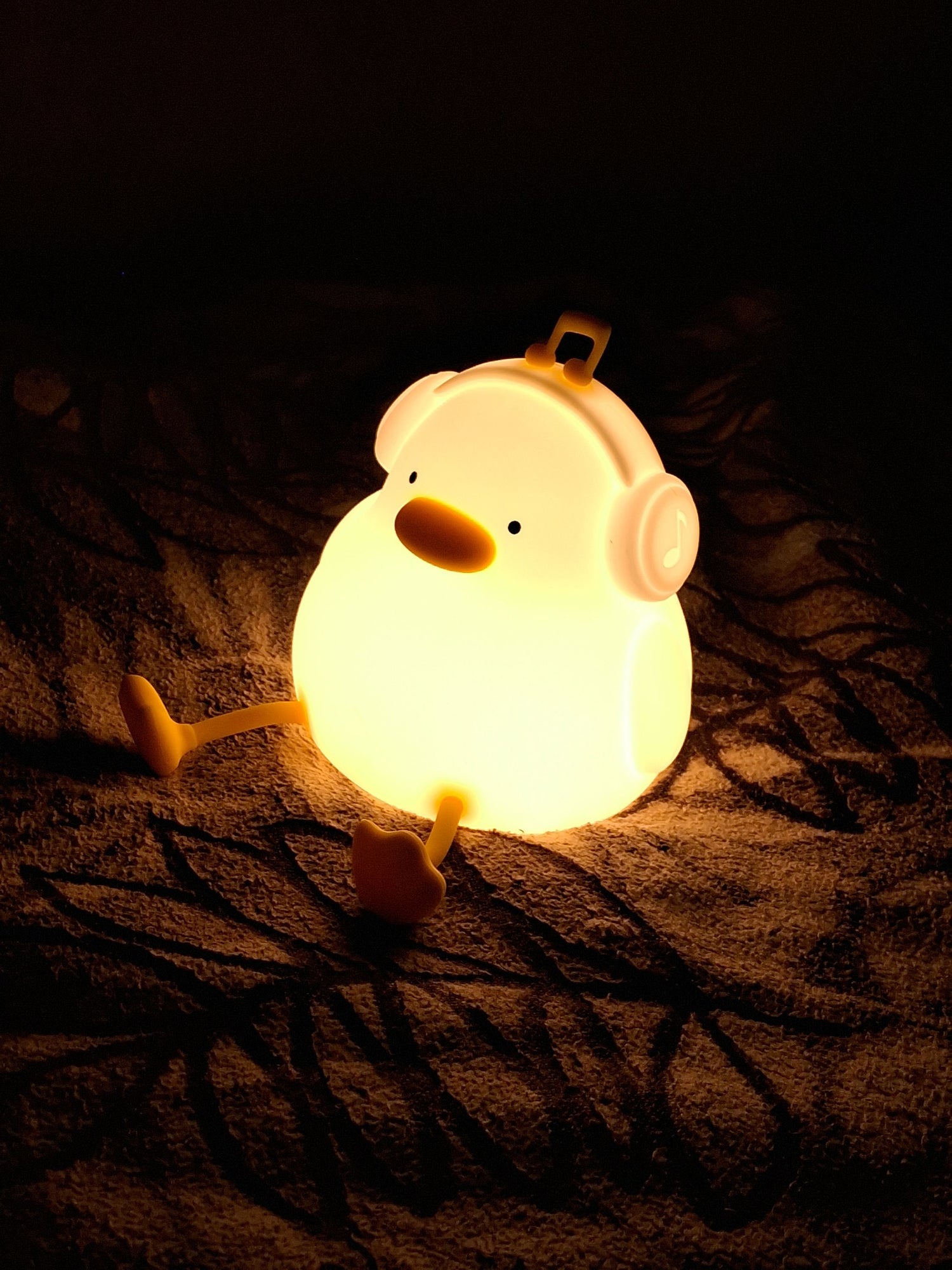 Duck night light glowing softly on a blanket in a dark room